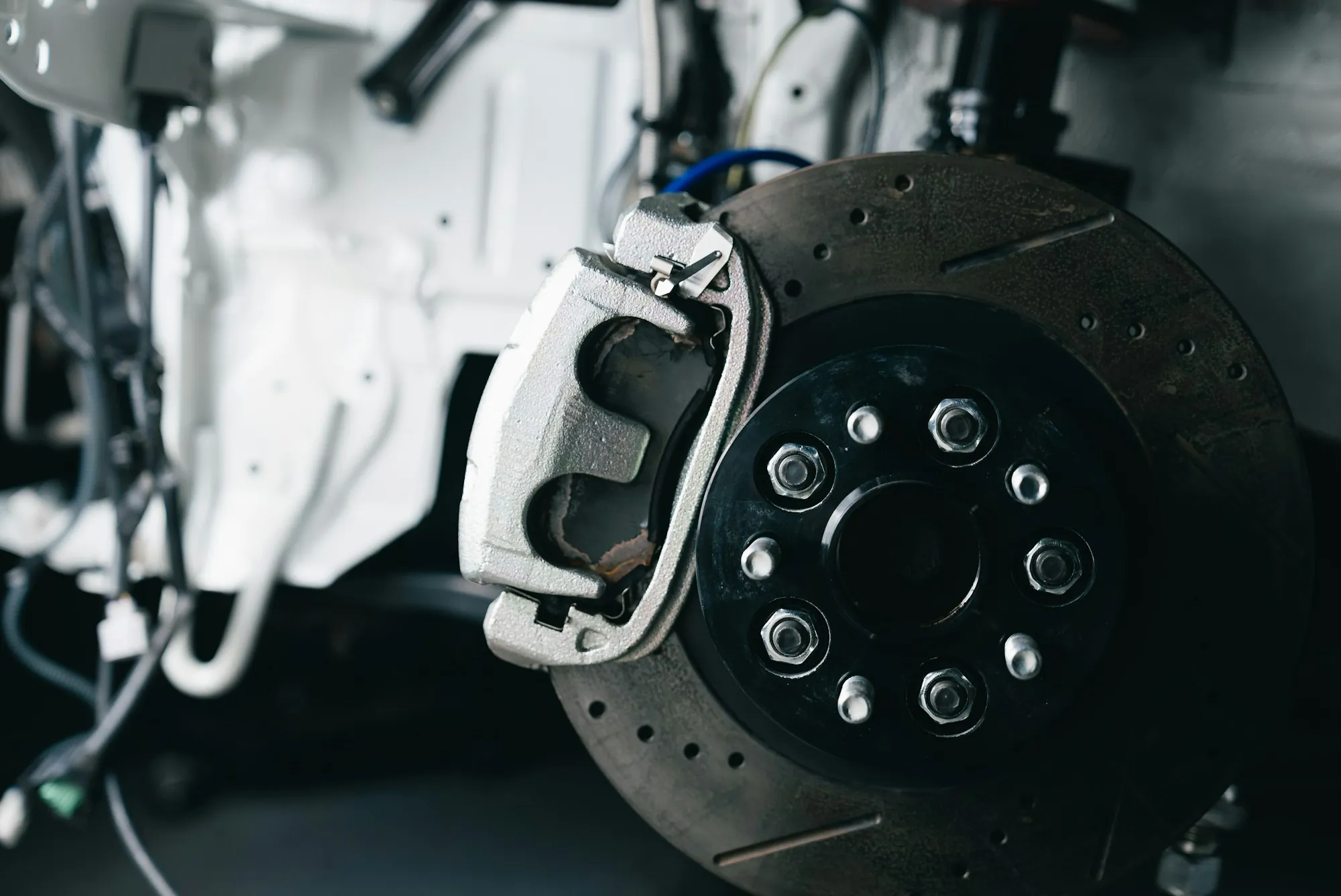 Brake rotor and caliper on a vehicle raised on a lift with the wheel removed