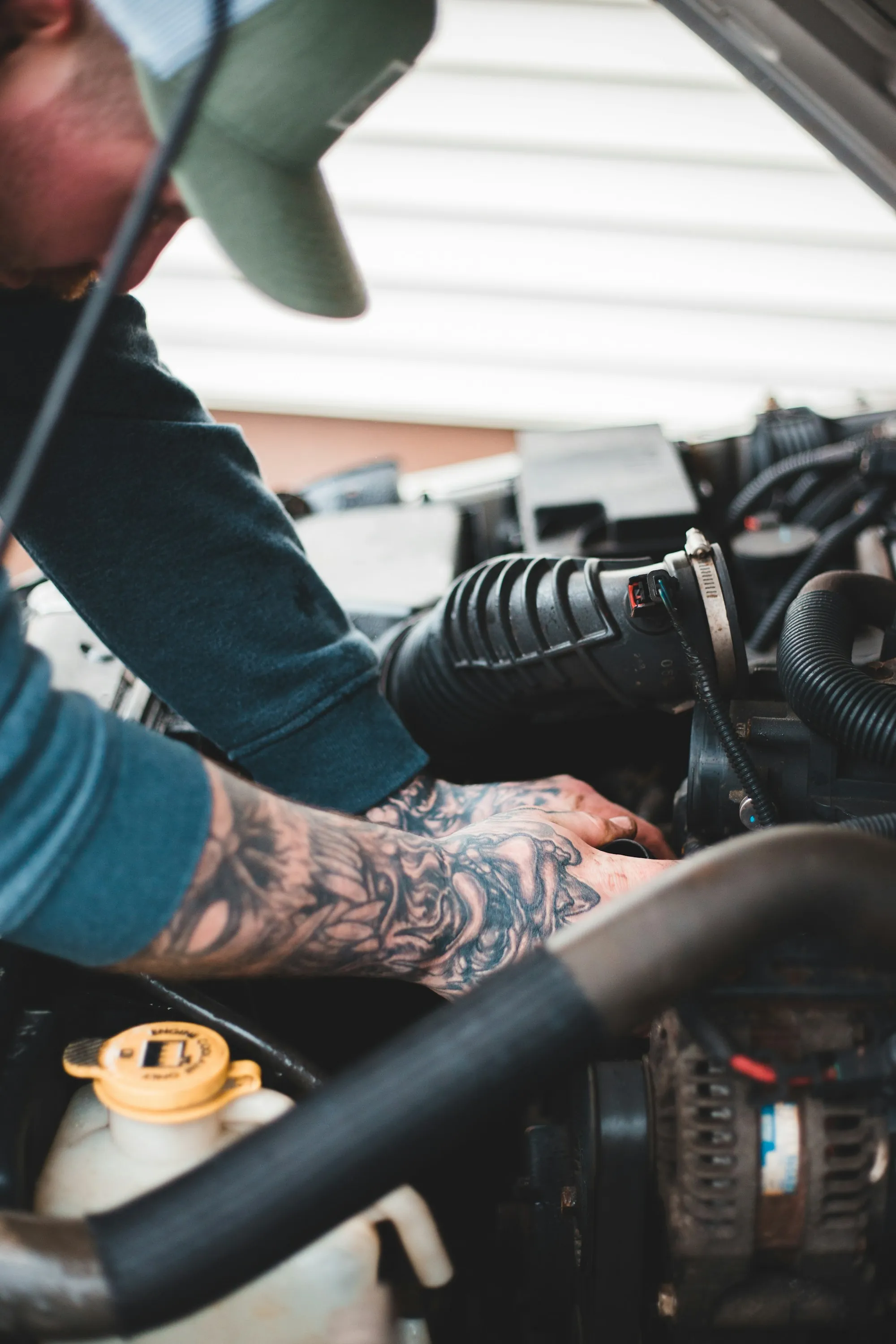 Mechanic with a tattooed forearm working on an engine