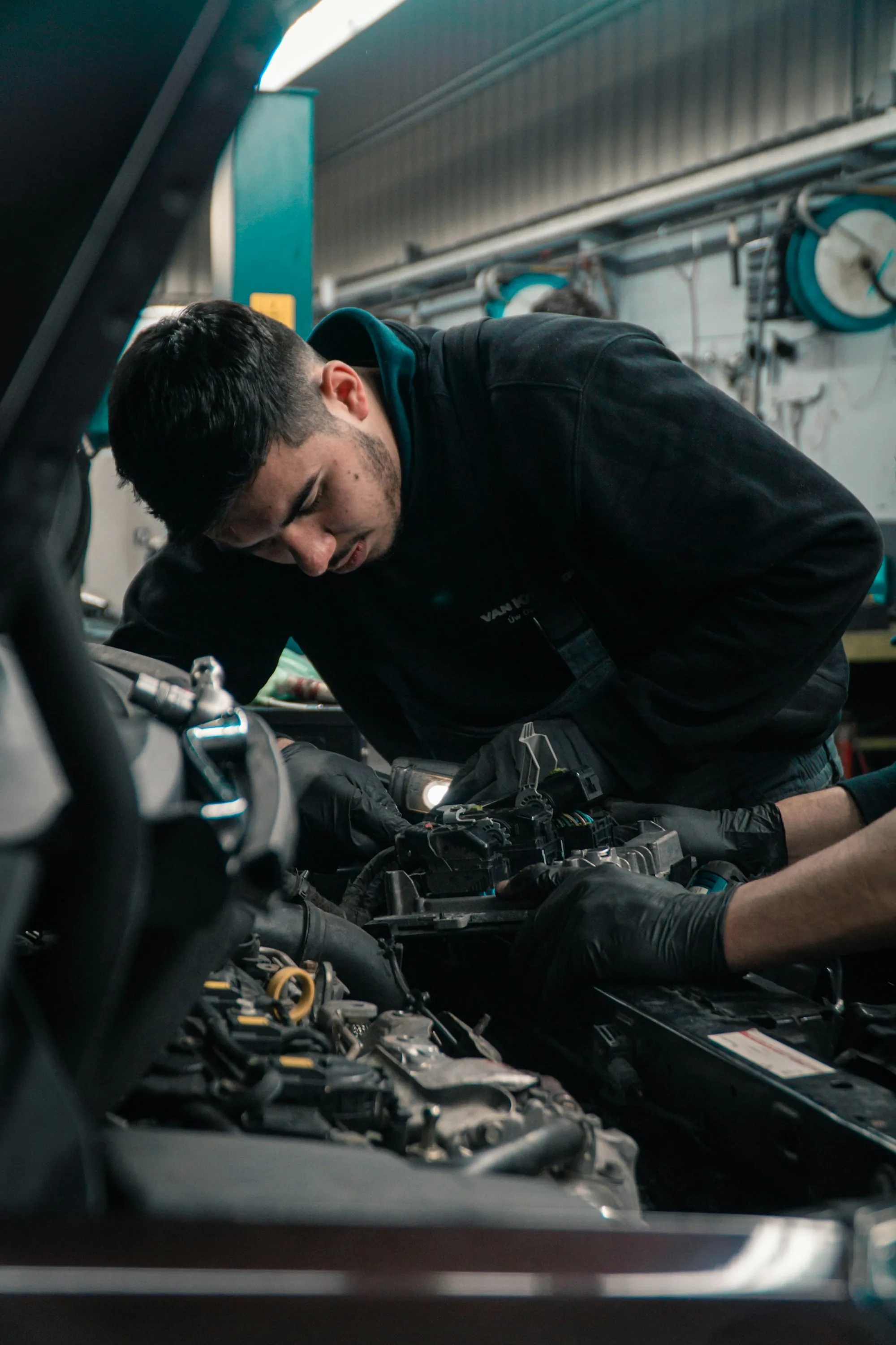 Technician bent over a running engine checking components by hand