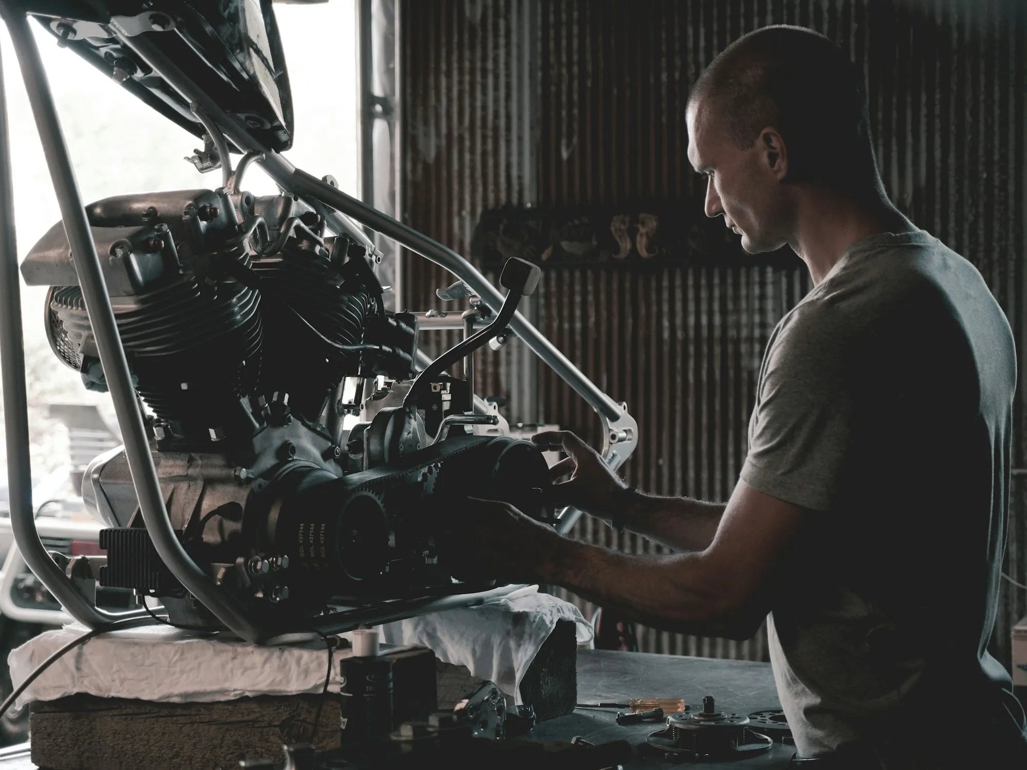Mechanic in a grey t-shirt working on an engine mounted on a shop stand