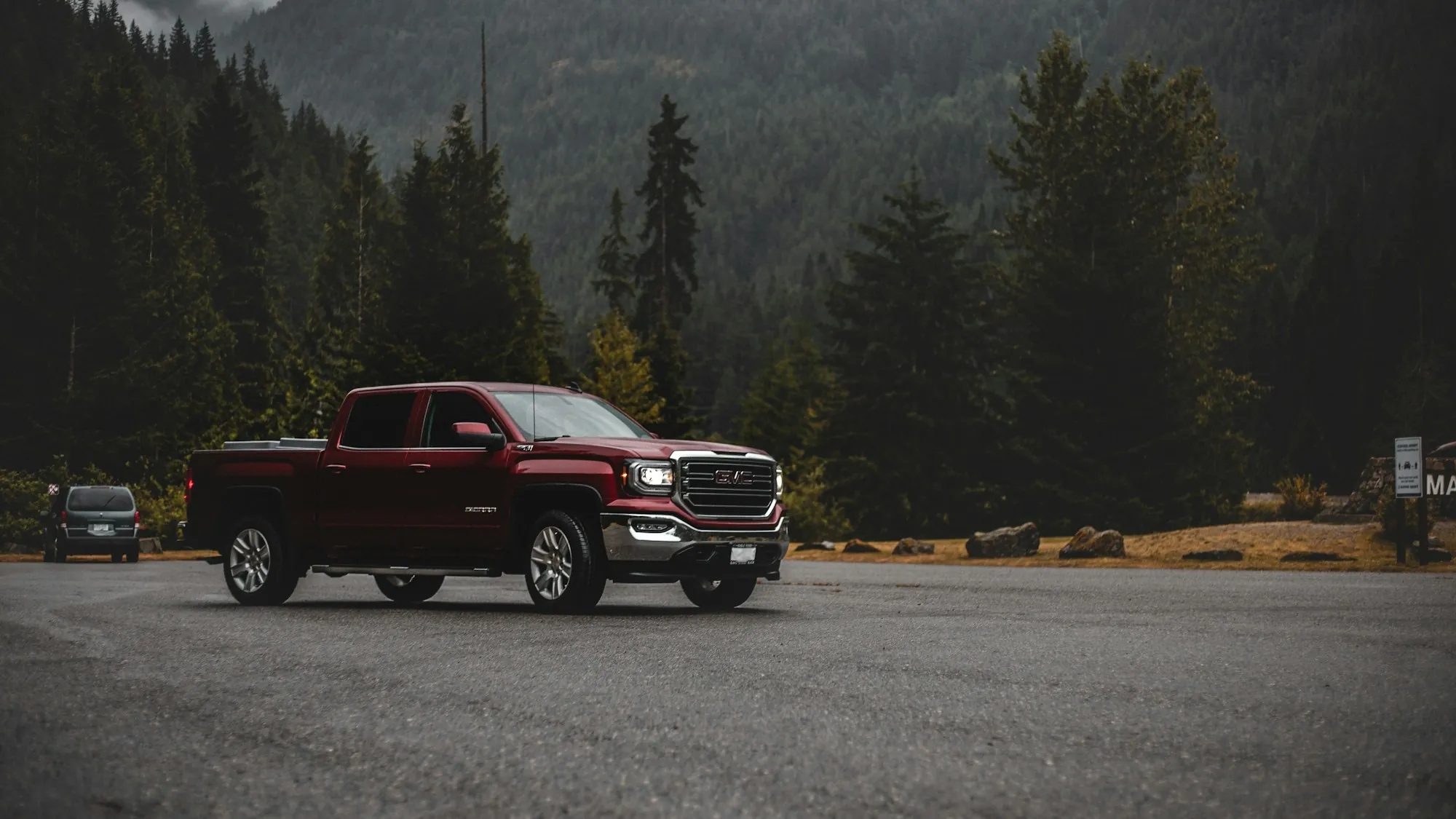 Red pickup truck on a mountain lot ringed by pine forest